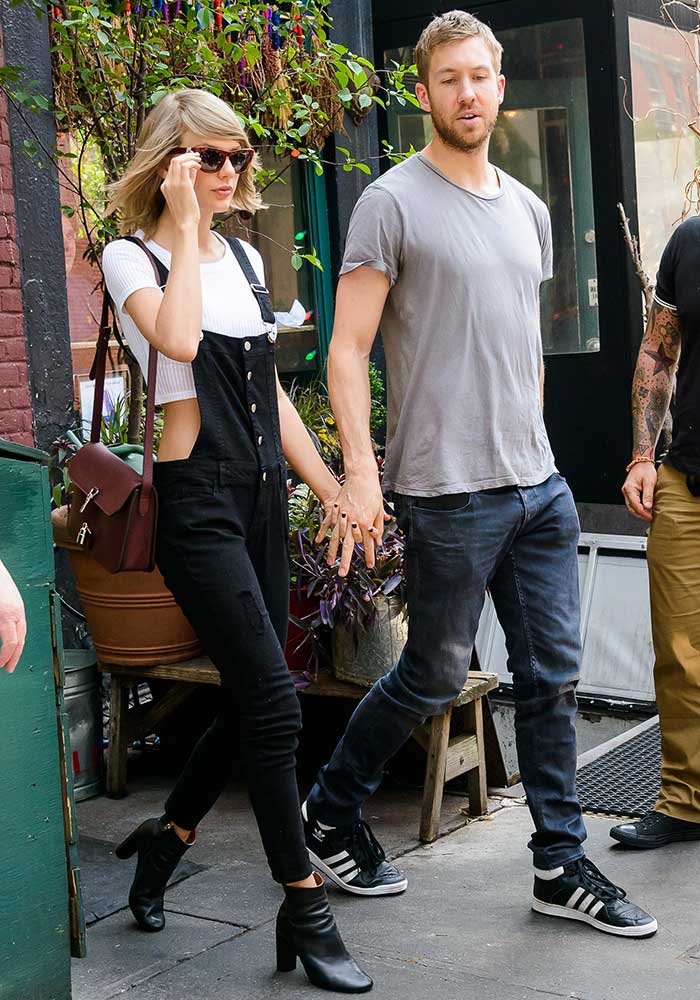 Taylor Swift holds hands with Calvin Harris, pairing her black dungarees and Topshop ankle boots with a Gucci bag, while Calvin keeps it casual in a grey t-shirt, dark jeans, and Adidas sneakers