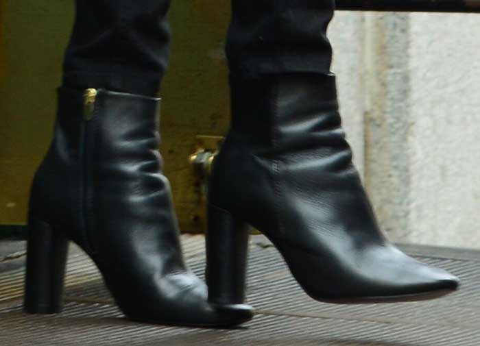 Taylor Swift’s Topshop “Magnum” ankle boots feature sleek leather, almond-shaped toes, and wrapped architectural block heels that add both height and polished sophistication to her look