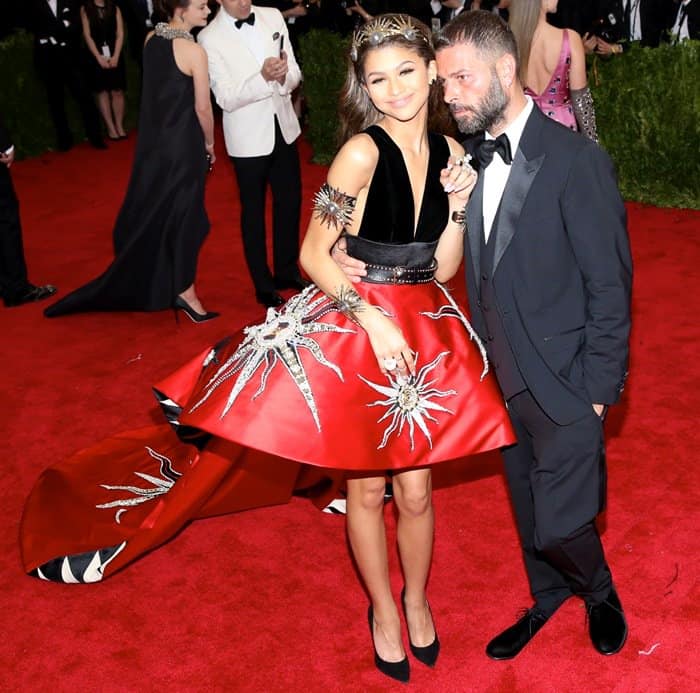 Zendaya poses with designer Fausto Puglisi, showcasing her striking red gown adorned with sun motifs and a black velvet bodice, at the 2015 Met Gala