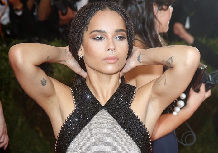 Zoë Kravitz exudes effortless confidence as she adjusts her braids, showcasing her chainmail Alexander Wang gown and signature delicate tattoos