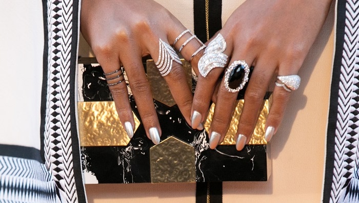 Her silver manicure and stacked statement rings perfectly complement a geometric black-and-gold Emm Kuo clutch