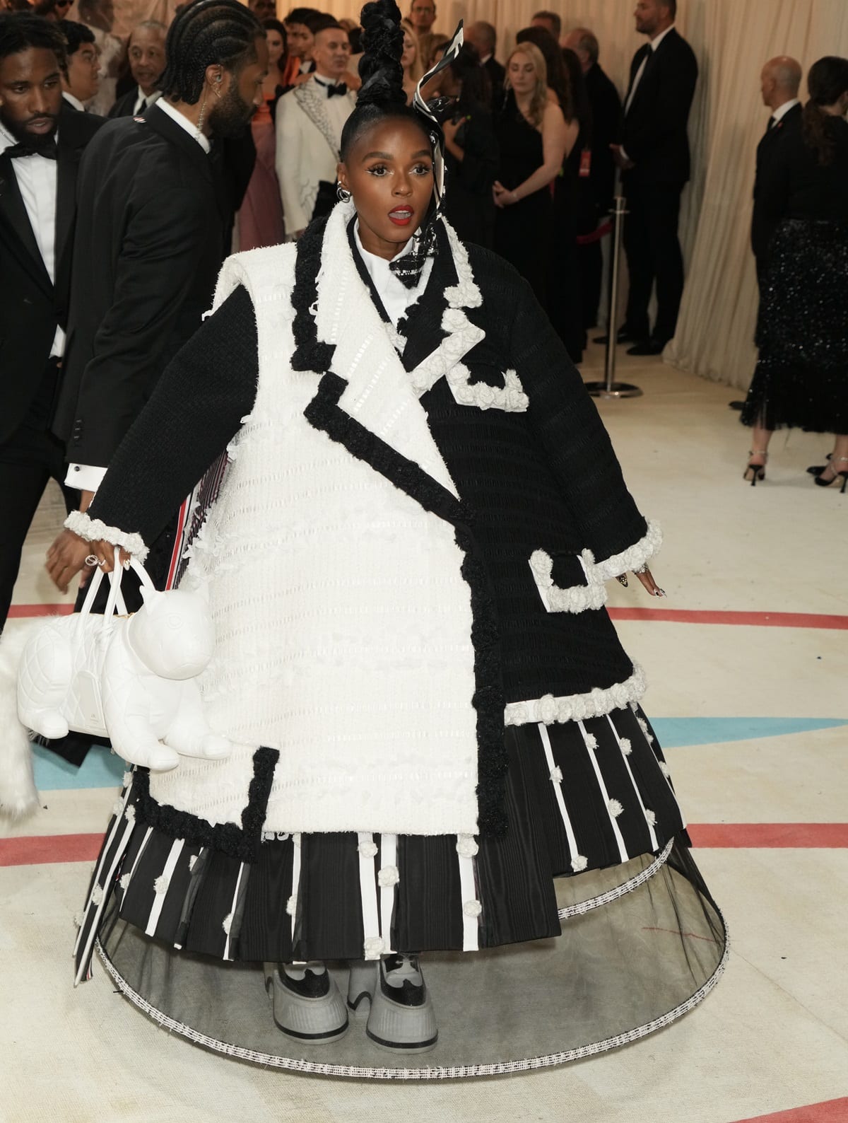 Janelle Monáe commands attention in an over-the-top black-and-white Thom Browne tuxedo-coat ensemble, revealing a sculptural tulle pannier and finishing the look with the brand’s space-inspired Astronaut Boots at the 2023 Met Gala