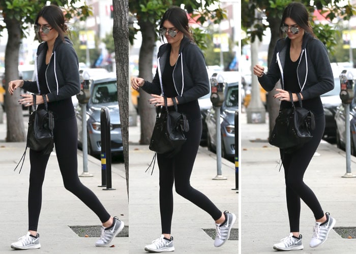 Kendall Jenner steps out in sporty chic style, pairing black leggings and a hoodie with metallic sneakers and her signature oversized sunglasses