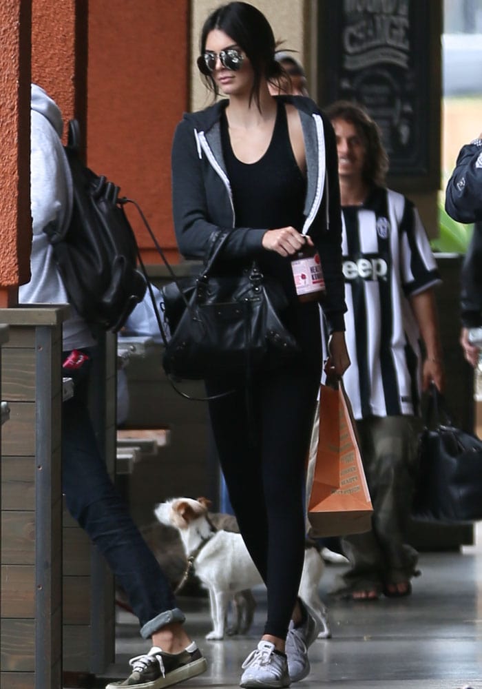 Kendall Jenner keeps it effortlessly cool with her hair pulled back into a casual, messy bun, pairing reflective sunglasses and minimal makeup with her sleek, sporty outfit for a laid-back yet stylish vibe