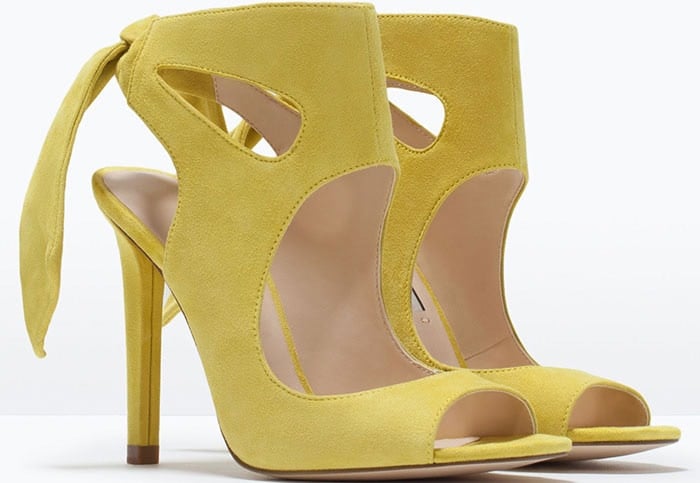 The sunshine-yellow suede heels feature elegant cutouts, an open peep toe, and a sleek stiletto heel balanced by a soft ankle tie for modern sophistication