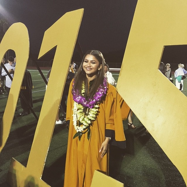 Zendaya celebrates her high school graduation, posing in her gold gown and leis next to a large '2015' sign, as shared on her Instagram on June 11, 2015