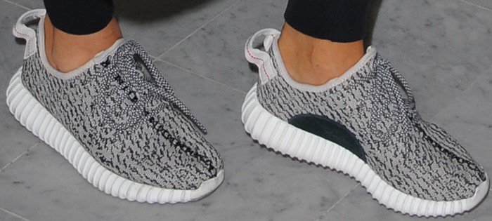 A close-up of Kim Kardashian’s Adidas Yeezy Boost 350 “Turtle Dove” sneakers, highlighting the grey-and-black Primeknit upper, rope laces, and ribbed white Boost sole that helped define the silhouette’s iconic sock-like fit