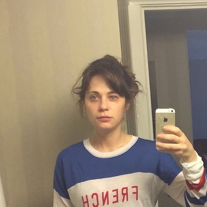 Zooey Deschanel sported a sleepy expression, tousled hair, and a loose-fitting shirt with the words "French Kissing in the U.S.A."