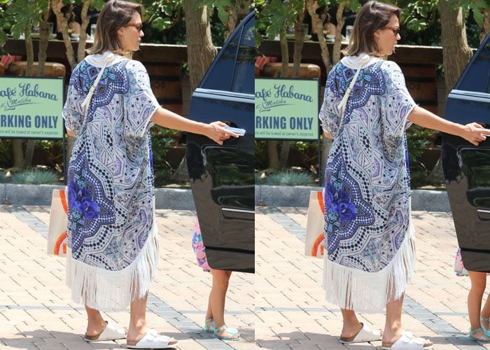 Jessica Alba effortlessly combines laid-back casual with high-end accessories, stepping out in denim cutoffs, a white tee, a fringed kimono, and classic white Birkenstock Arizona sandals