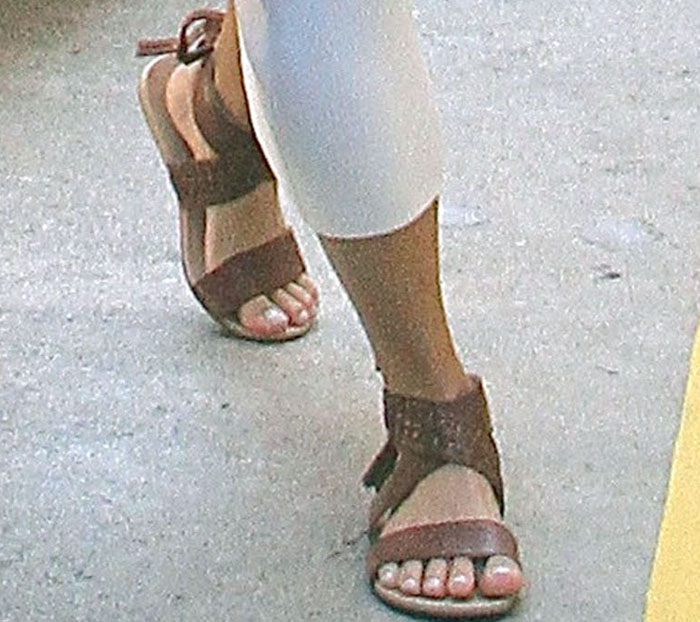 A close-up highlights the braided leather ankle detail and flat silhouette of Vanessa Hudgens’ Koolaburra “Alexa” gladiator sandals, grounding her breezy summer look with textured boho polish