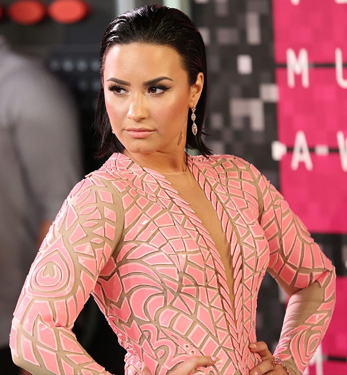 Demi Lovato looked fierce and seductive, thanks to her slicked-back raven hairstyle and gorgeous makeup with smoky eyeshadow, winged eyeliner, bronzed blush, and pale pink lip gloss