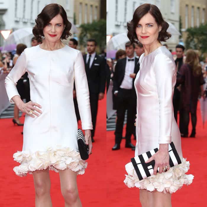 Elizabeth McGovern captivates in a sleek white dress with rosette details, complemented by a bold striped clutch on the red carpet