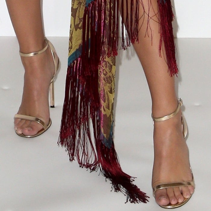 Emily Ratajkowski highlights her polished pedicure in metallic strappy Jimmy Choo ‘Minny’ sandals, adding a sleek finish to her fringed Oscar de la Renta look at TheWrap’s Power Women Summit