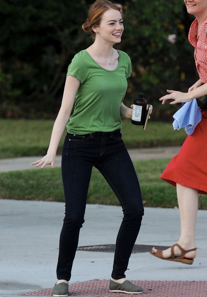 Emma Stone wore her hair in a relaxed, low bun with a subtle side part, perfectly complementing her playful energy as she shared a laugh and struck a lighthearted pose on set