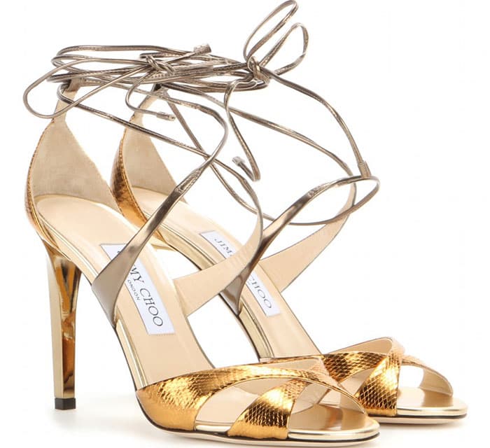 The Jimmy Choo “Teira” lace-up sandals in metallic snakeskin pair delicate wraparound laces with a luminous, statement-making heel