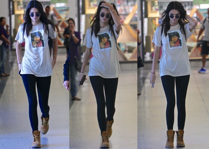 Kendall Jenner styled her casual airport look with a John Lennon graphic tee, tight black yoga pants, and classic Timberland boots