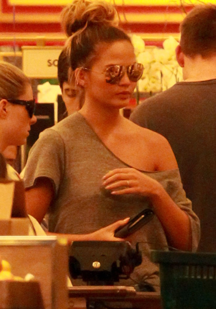 Inside Bristol Farms, Chrissy Teigen balances laid-back styling with statement accessories, including reflective aviator sunglasses