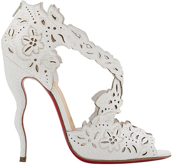 Christian Louboutin “Decoupadiva” heels in white leather feature intricate laser-cut floral detailing, a sculptural ankle cage, and a towering stiletto finished with the brand’s signature red sole