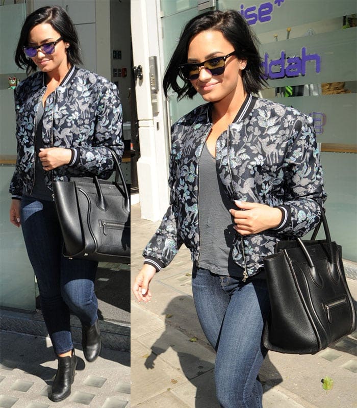 Demi Lovato steps out in casual-chic style, pairing a deer-printed bomber jacket with skinny jeans, ankle boots, and a black Celine tote while leaving a London office on September 10, 2015