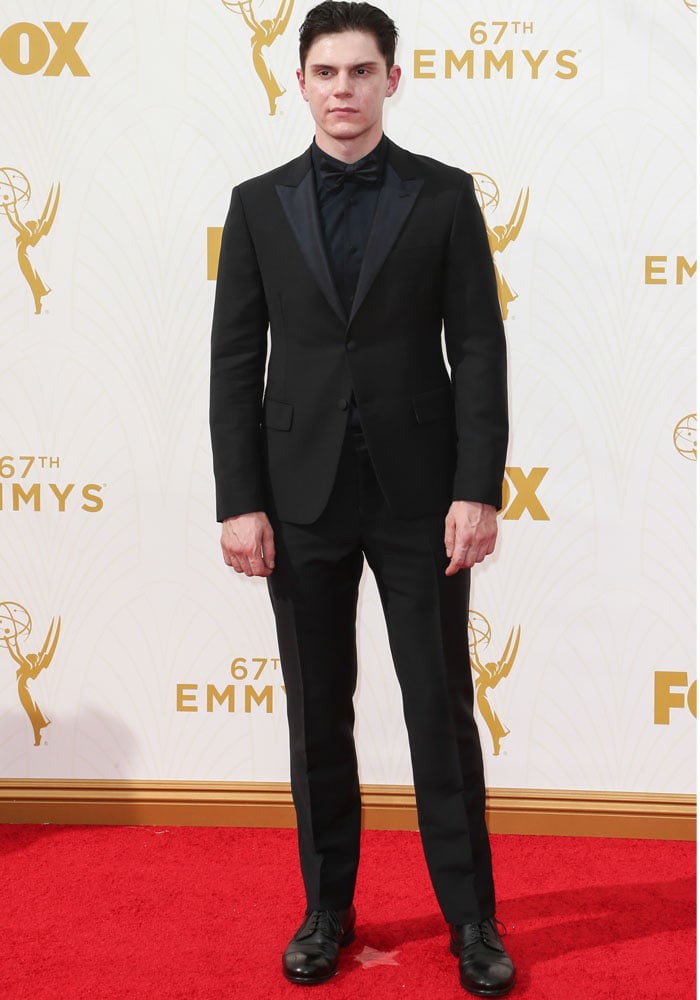 Evan Peters steps onto the red carpet at the 67th Primetime Emmy Awards in Los Angeles on September 20, 2015, wearing a sleek black Prada suit with matching dress shoes