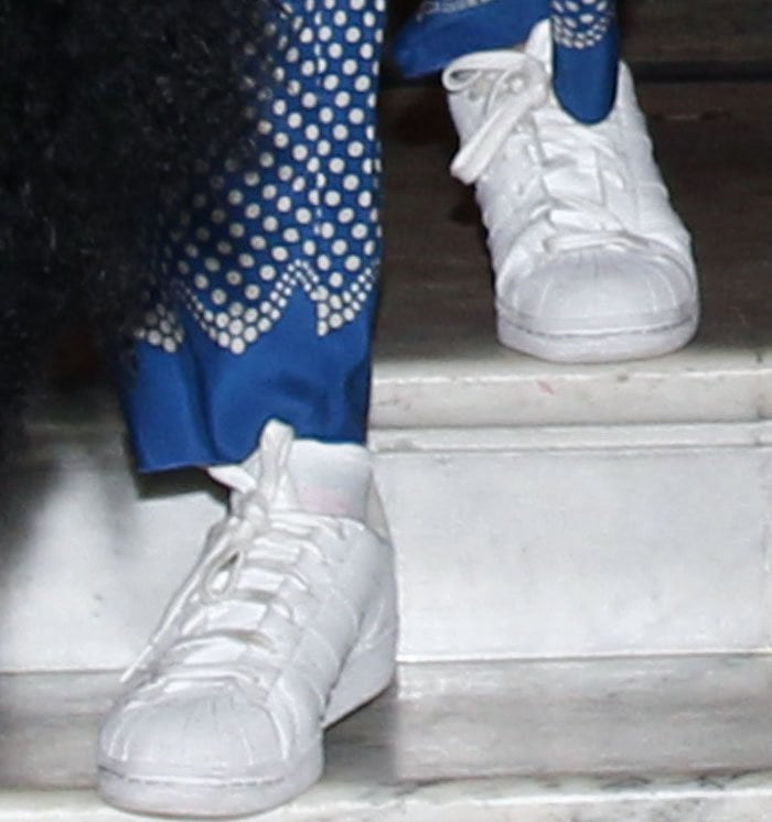 A close-up highlights the well-worn white Adidas Superstar sneakers, their signature shell toes grounding the outfit in classic streetwear heritage