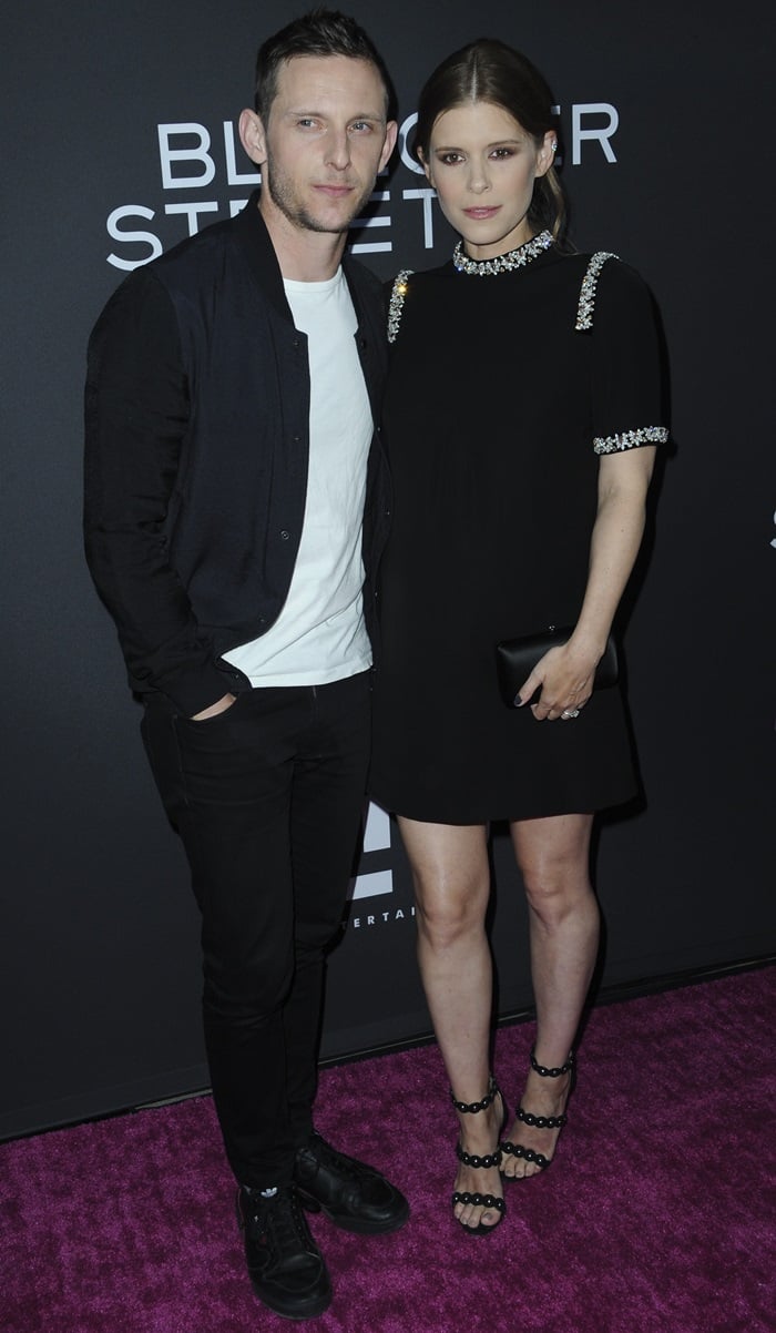 Jamie Bell and Kate Mara attend the Teen Spirit premiere at ArcLight Hollywood on April 2, 2019, with Mara in an embellished Prada LBD—crystal-trimmed at the neckline and sleeves—styled with a sleek low bun, smoky eyes, a black clutch, and strappy statement heels that add texture to the minimalist silhouette