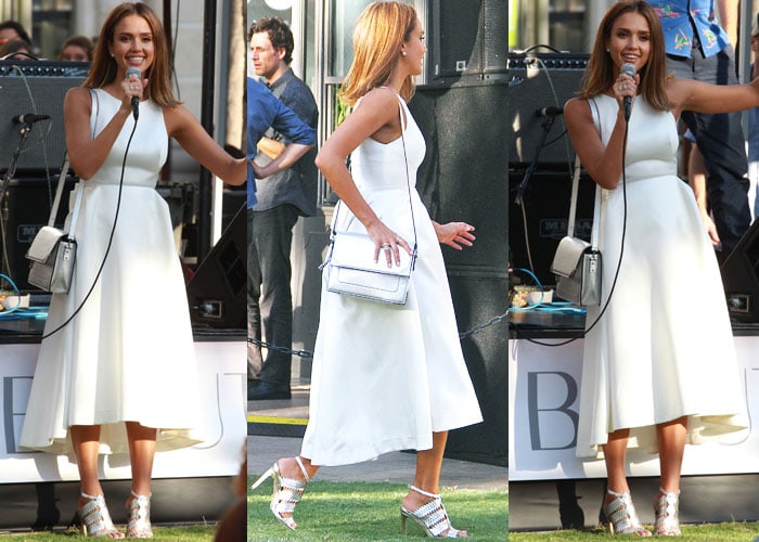 Jessica Alba speaks during an Honest Beauty event at The Grove in Los Angeles, pairing a sleeveless white midi dress with metallic laser-cut Eight Fifteen “Bonfire” heels and a structured silver handbag