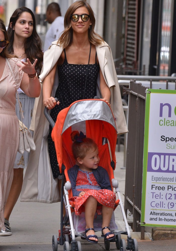 Jessica Alba layers a sweeping cream trench over her fitted polka-dot dress while navigating the streets of Soho with daughter Haven
