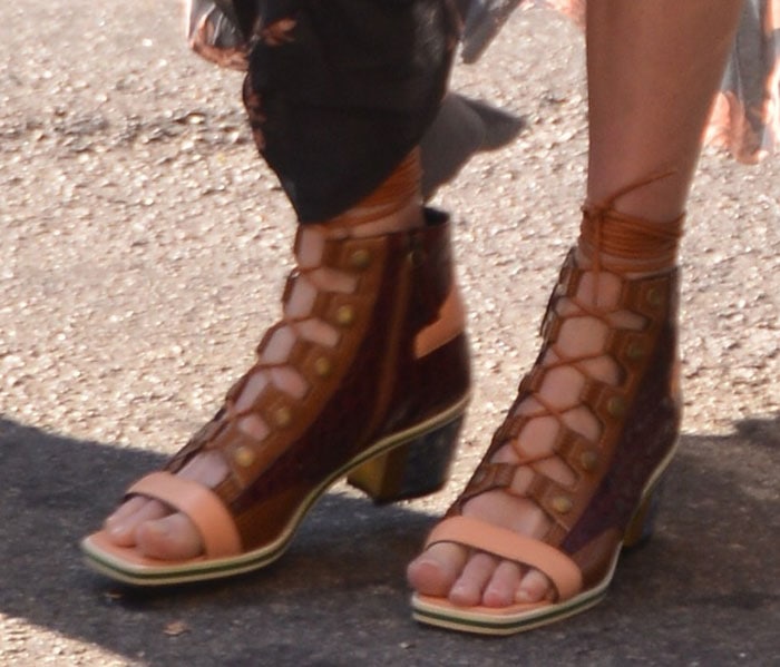 Kate Bosworth showcases her nude pedicure in Rodarte’s unique gladiator-inspired lace-up sandal booties featuring croc-embossed leather, brass-toned studs, and marble acrylic block heels