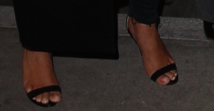 Kim Kardashian steps through LAX in Manolo Blahnik “Chaos” sandals, the slim toe strap and delicate ankle band creating a clean, barely-there line that contrasts with her structured travel layers