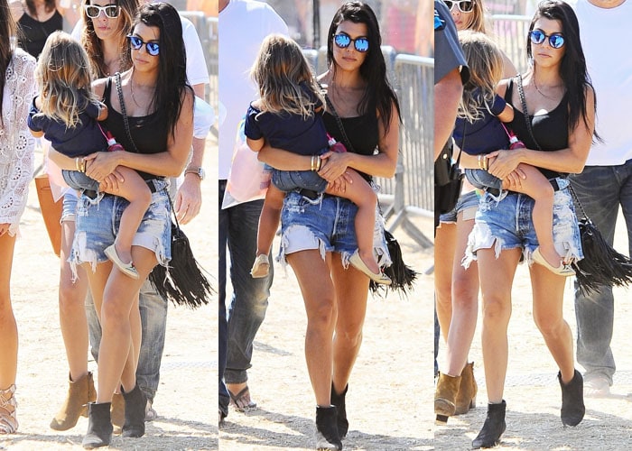 Kourtney Kardashian wears a black top by Lanston and destroyed denim shorts by Levi's