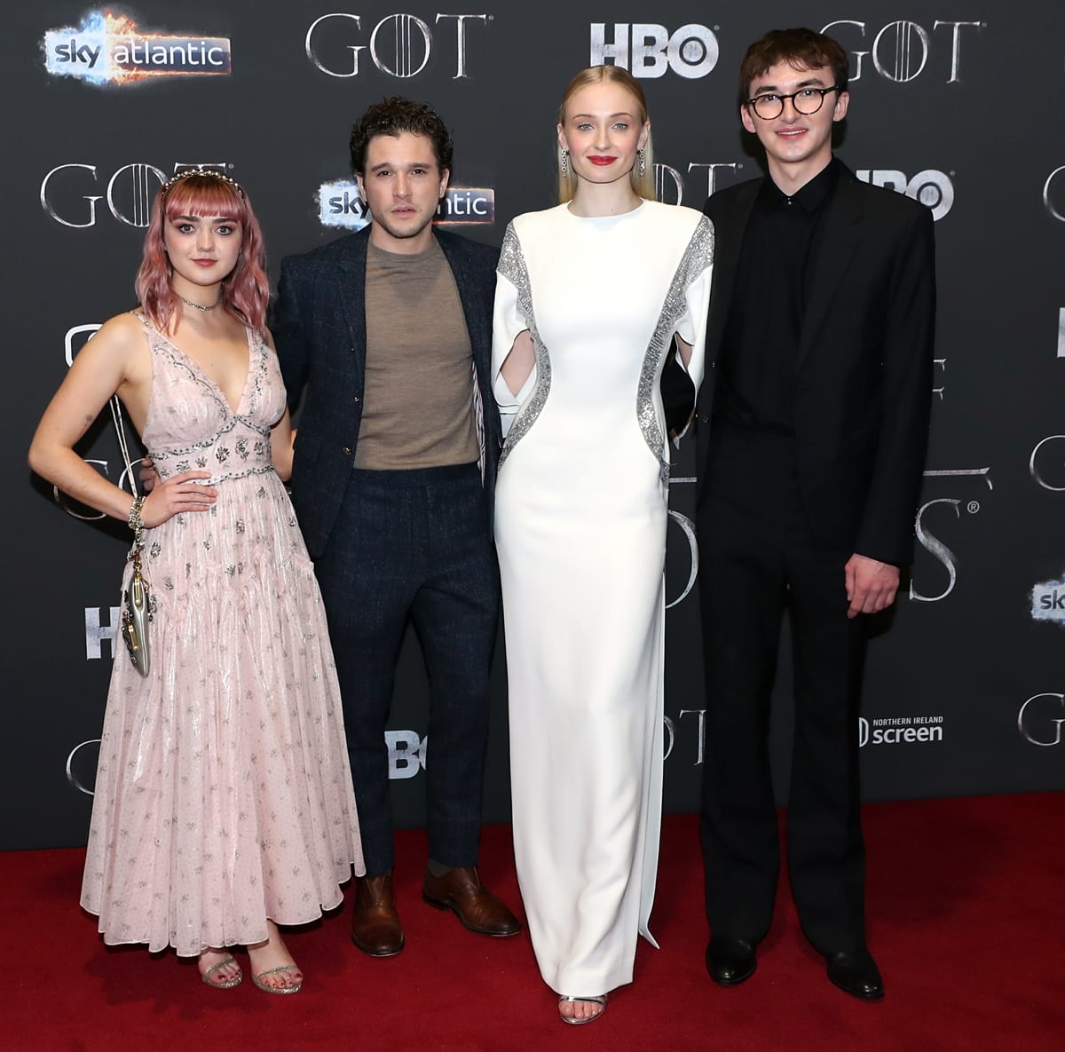 Maisie Williams, Kit Harington, Sophie Turner, and Isaac Hempstead Wright reunited in stylish eveningwear at the Game of Thrones Season 8 premiere in Belfast on April 12, 2019, with Maisie and Sophie showcasing their dramatically different heights in metallic sandals and a sleek white gown, respectively