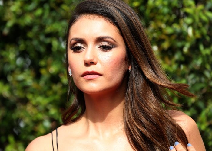 Nina Dobrev touches her long brunette locks as she attends the Creative Arts Emmy Awards