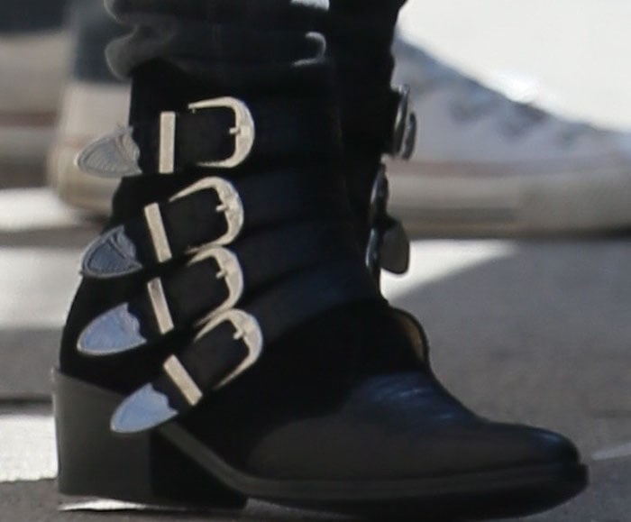 A close-up reveals the Toga Pulla ankle boots’ stacked heel, almond toe, and signature silver buckled straps