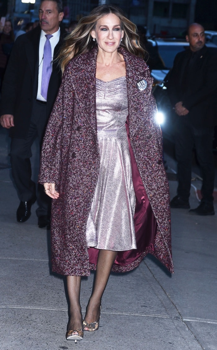 Sarah Jessica Parker arrives for The Late Show in a shimmering metallic pink dress topped with a textured burgundy coat, finishing the look with what appears to be her signature glittery SJP “Naomi” peep-toe pumps