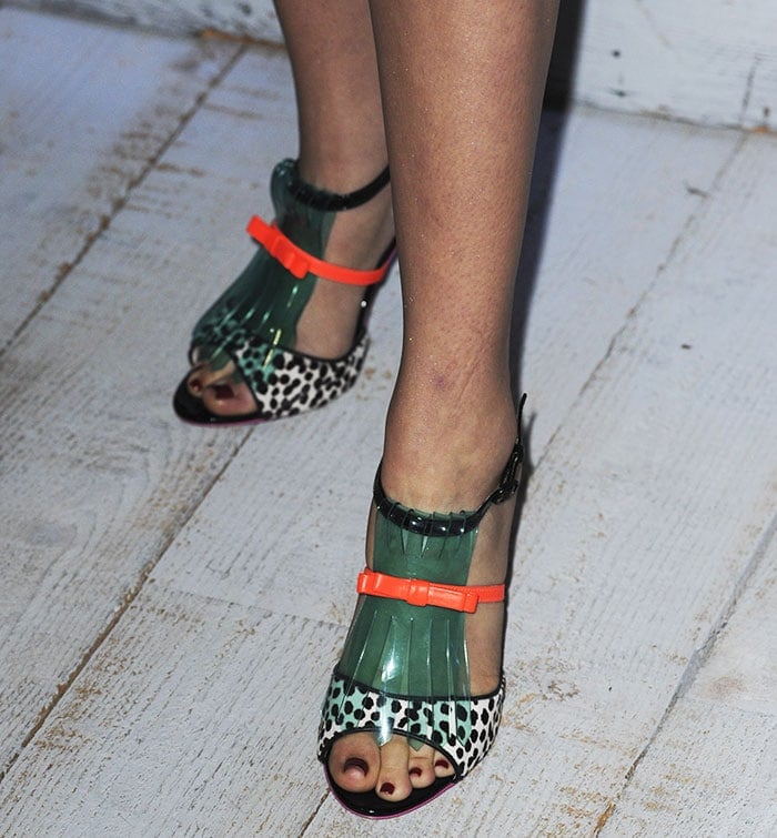 Zoey Deutch showed off her dark burgundy pedicure in Sophia Webster’s playful “Verity” sandals, featuring polka-dot calf hair, transparent green vinyl fringe, and neon orange accents