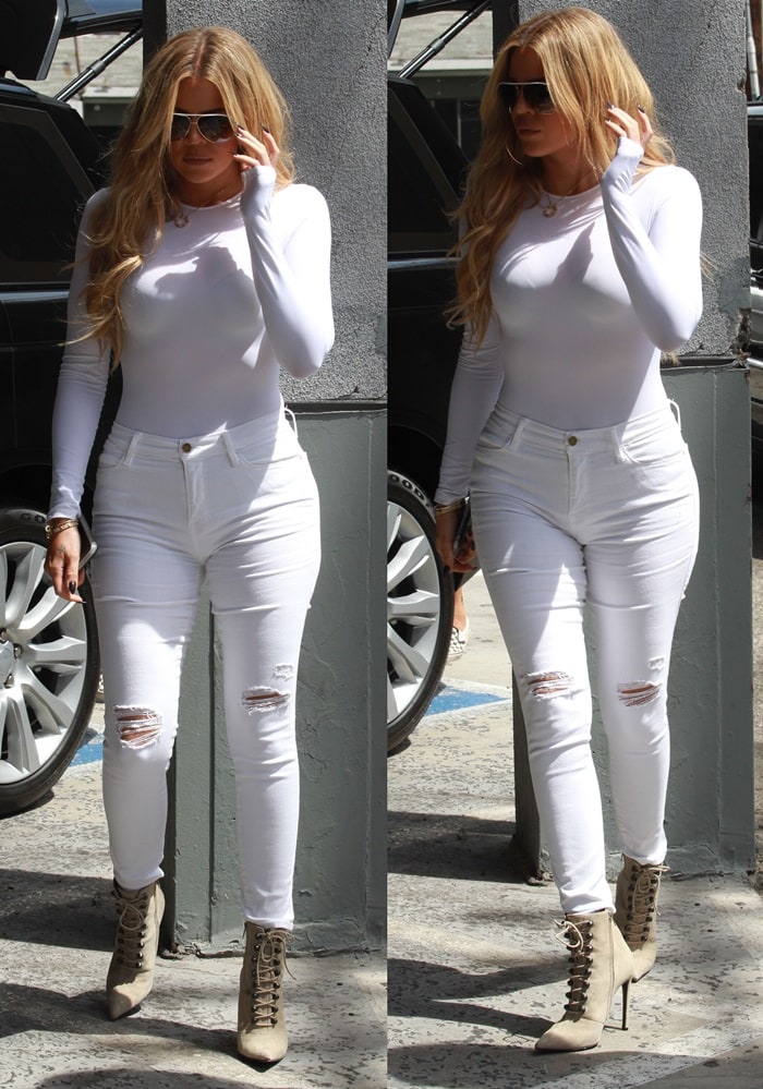 Khloé Kardashian hides her eyes behind a pair of aviator shades as she clutches her cellphone in one hand