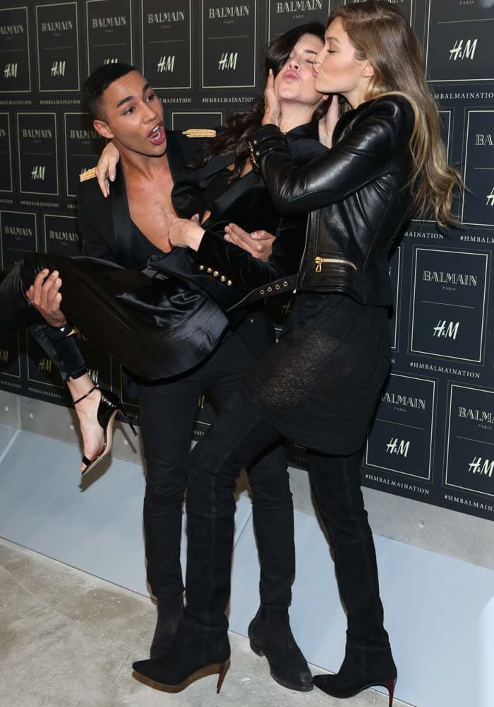 Gigi Hadid and Kendall Jenner share a playful moment with Balmain's Creative Director, Olivier Rousteing