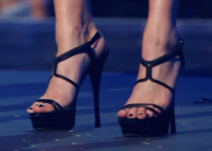 Hailey Baldwin elevates the look with sleek black Versace platform sandals featuring delicate straps and sky-high stiletto heels