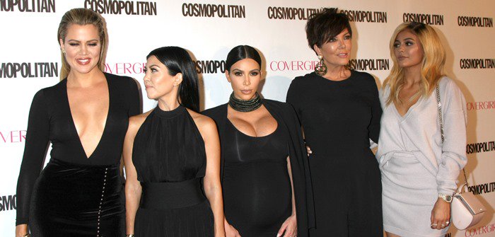 Khloé Kardashian, Kourtney Kardashian, Kim Kardashian, Kris Jenner and Kylie Jenner all pose in front of a branded backdrop
