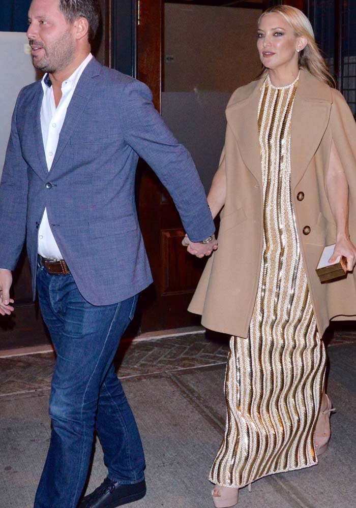 Kate Hudson holds hands with her agent, Michael Kives, while leaving the Rock the Kasbah premiere in New York City, layering a camel cape coat over her embellished Balmain gown and towering Brian Atwood “Tribeca” platform heels