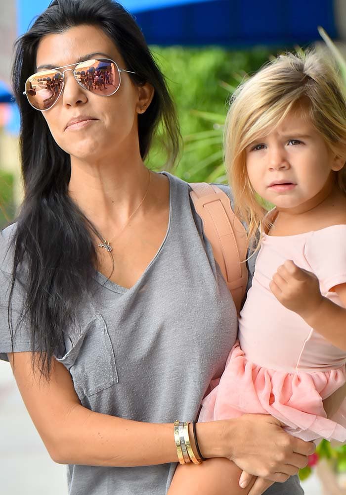 Kourtney Kardashian carries daughter Penelope Disick while heading to ballet class in Encino on October 14, 2015, dressed casually in a slouchy gray tee and mirrored aviator sunglasses
