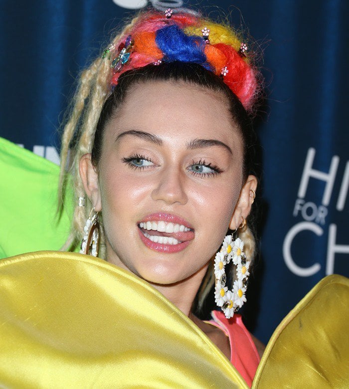 Miley Cyrus highlights her playful Gasoline Glamour Swan River daisy hoop earrings, a quirky accessory that perfectly complements her eccentric look
