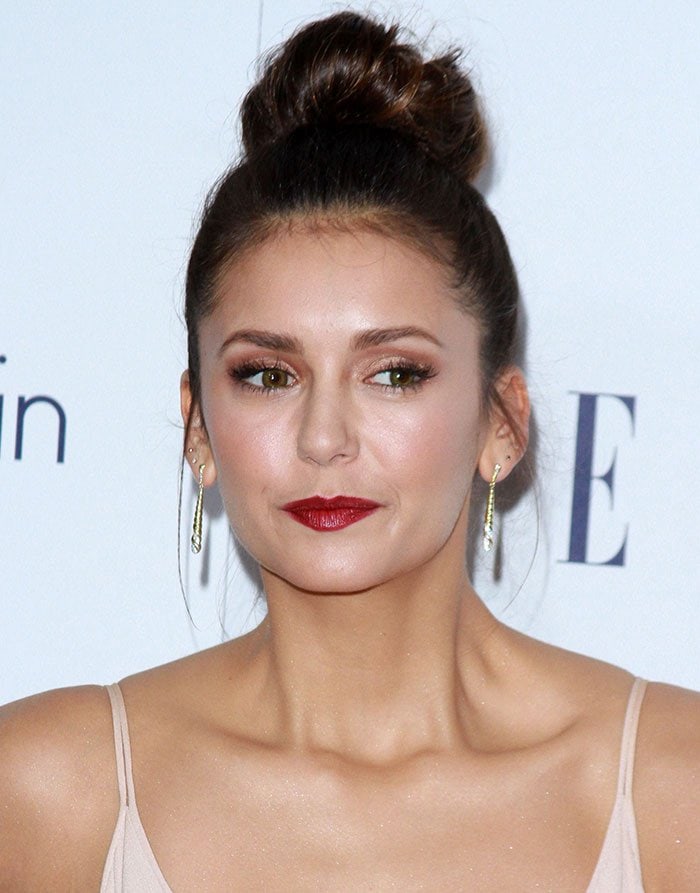 Nina Dobrev's hair was swept up into a high bun, while her face was gorgeously made up with a slick of red lipstick