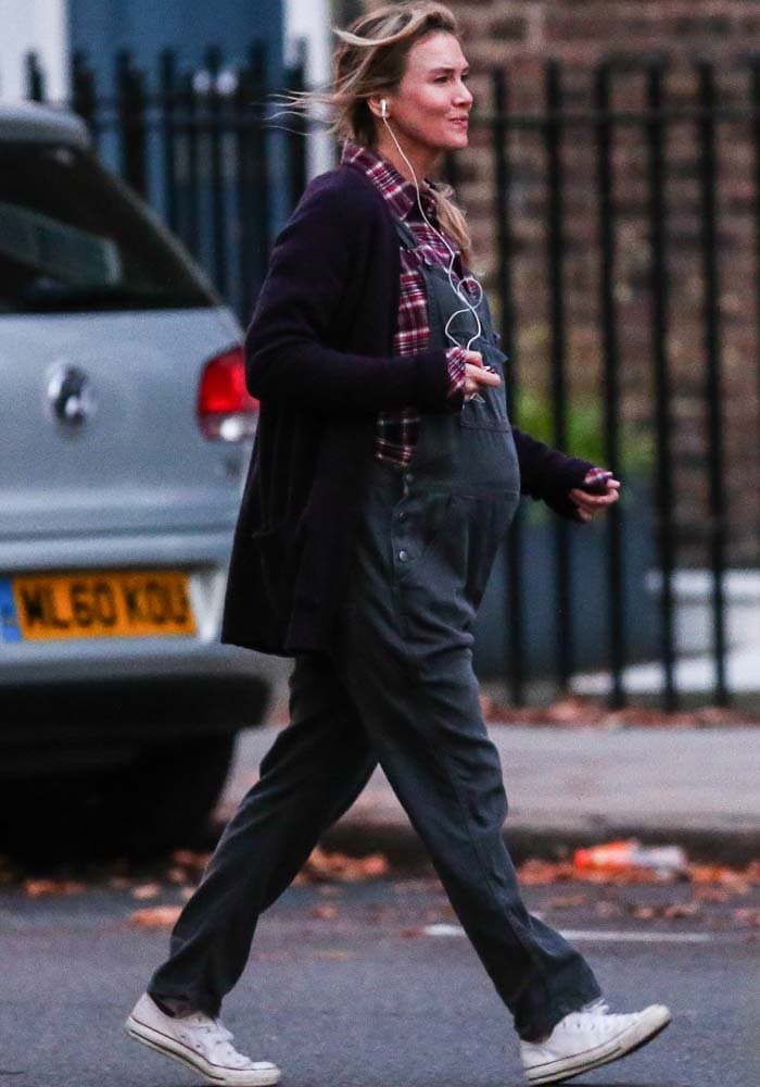 Renée Zellweger steps through a London street scene in character, debuting Bridget Jones’s faux baby bump styled with classic white Chuck Taylor sneakers