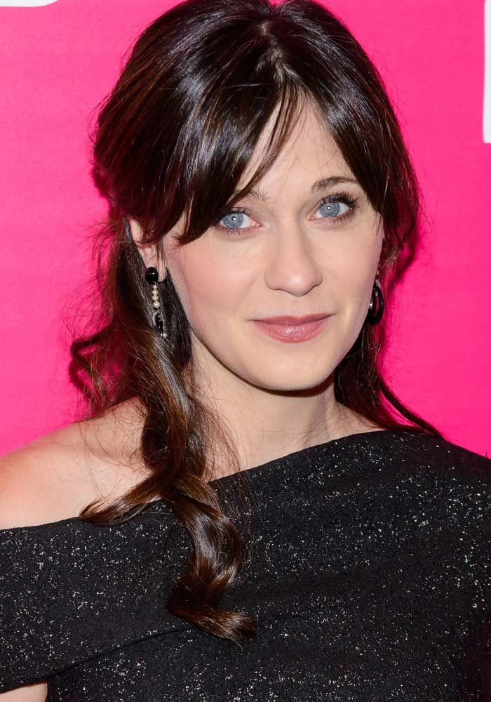 Zooey Deschanel combined metallic texture, side-swept bangs, and understated accessories for an elegant post-baby premiere appearance