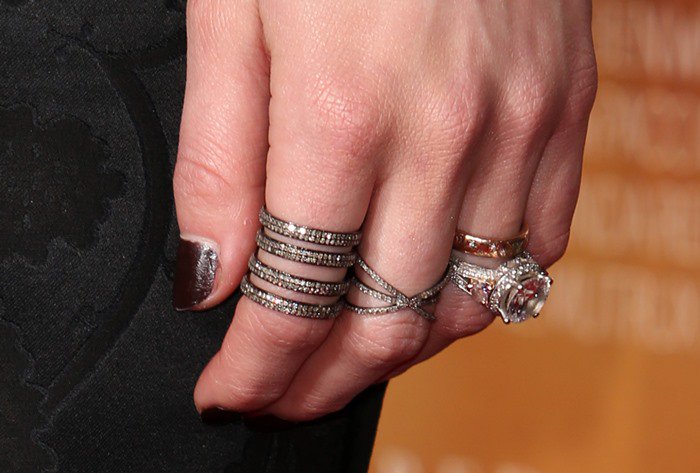 A close-up of Amber Heard’s hand shows her stacked diamond rings and dark metallic nail polish