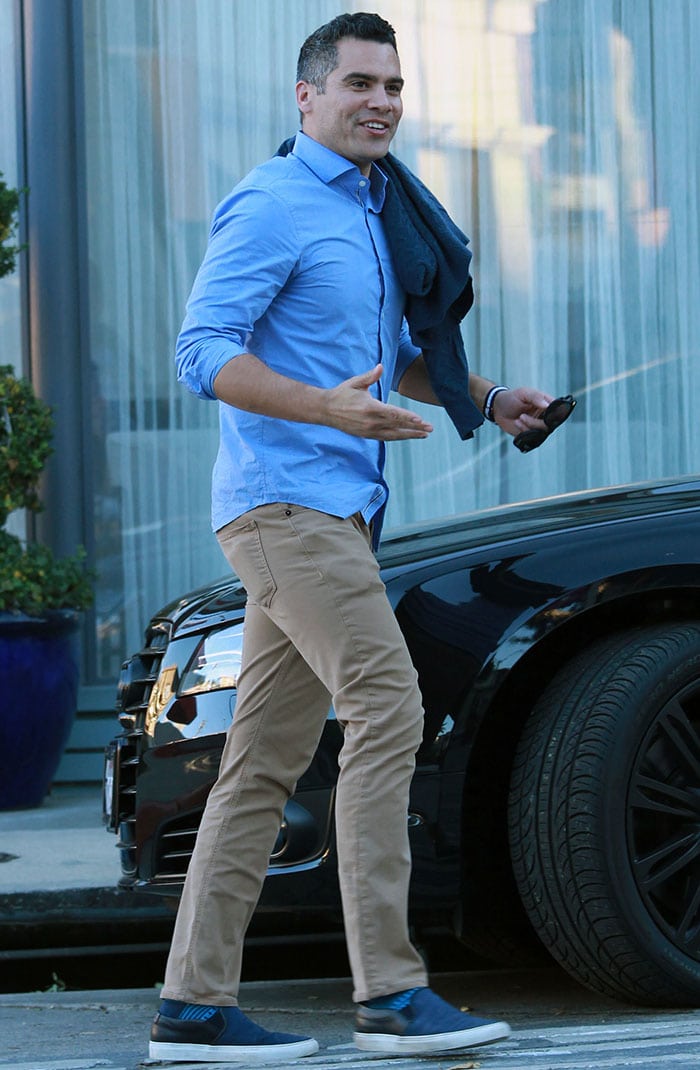 Cash Warren keeps things casual in a light blue button-down shirt, slim khaki trousers, and navy slip-on sneakers while leaving a birthday dinner in West Hollywood