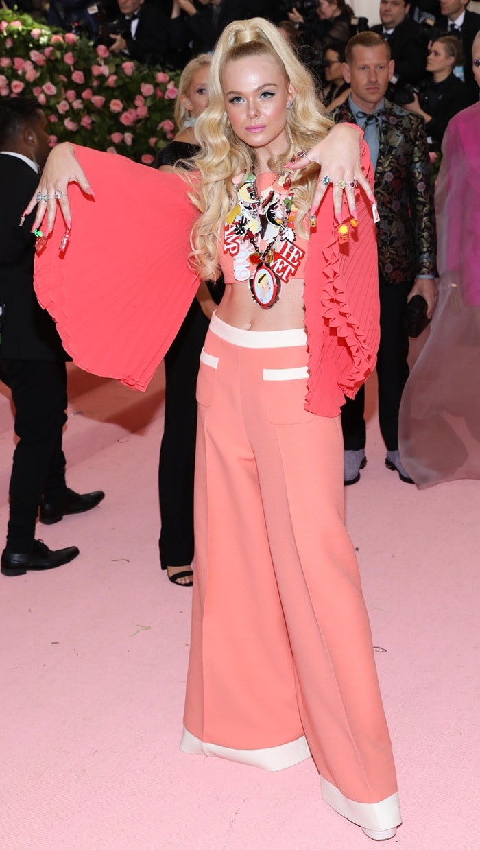 Elle Fanning fully embraced retro camp at the 2019 Met Gala by pairing her I Dream of Jeannie–inspired Miu Miu ensemble with towering platform heels, using the exaggerated height to amplify the playful proportions and anchor the wide-leg silhouette on the pink carpet