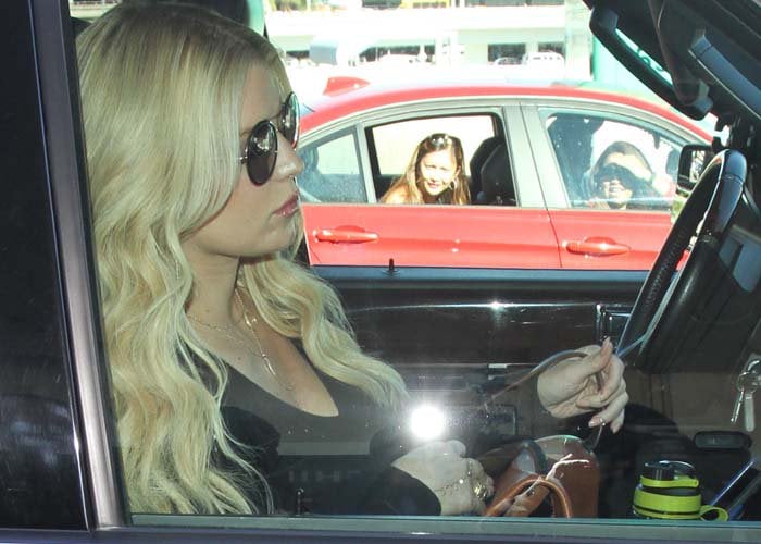 Jessica Simpson sits in a car at LAX wearing Gucci sunglasses and layered jewelry
